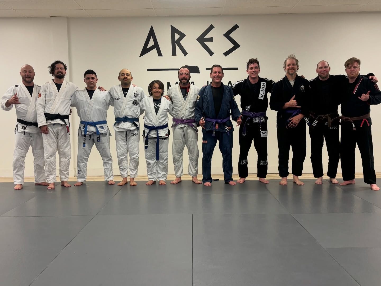 Ares BJJ Omaha adult class group photo in front of the Ares Omaha wall