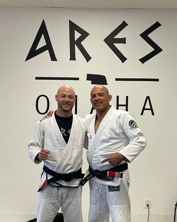 Prof. Ernesto James with his instructor in front of the Ares Omaha wall