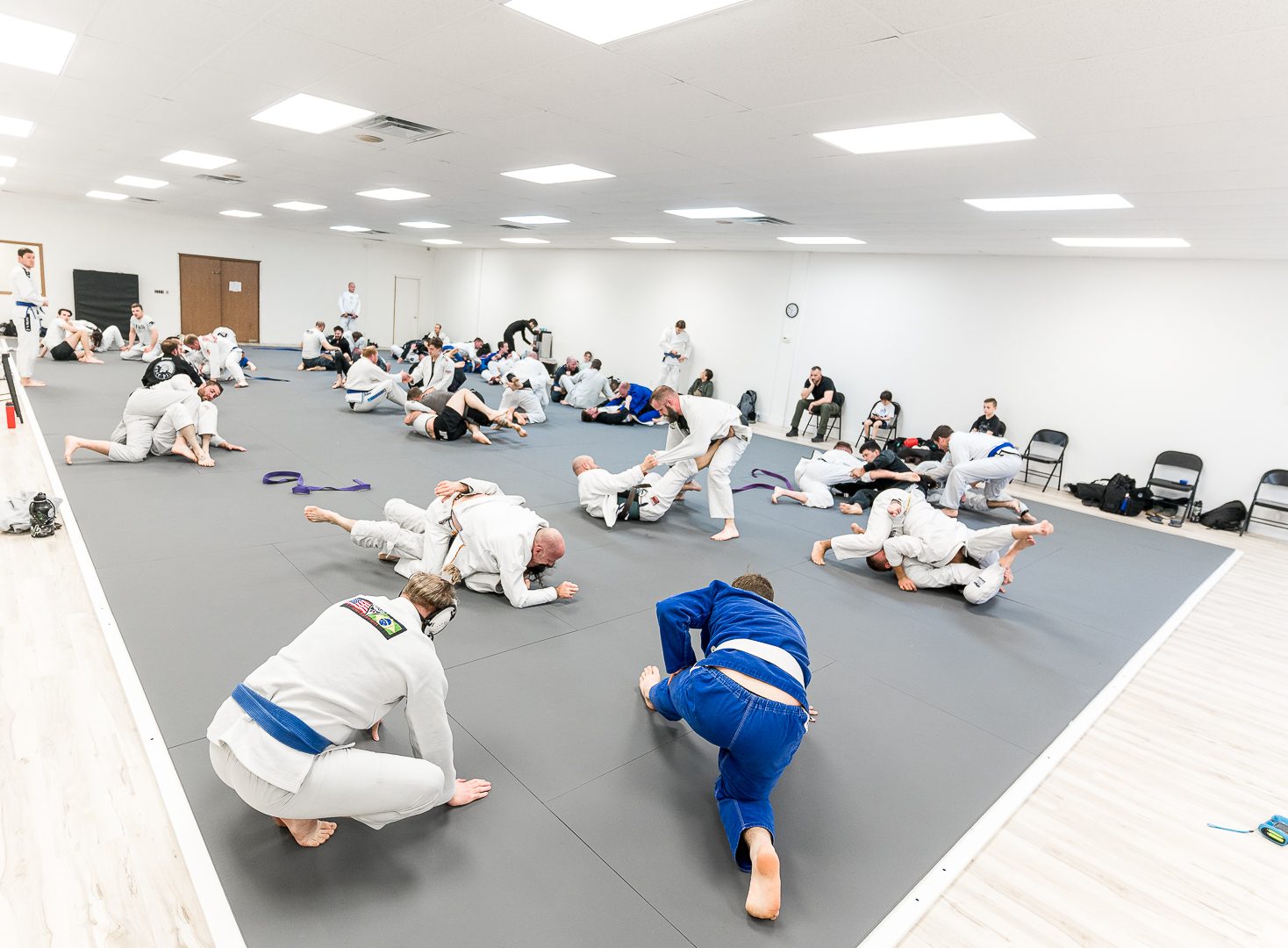 A full class of students training Brazilian Jiu-Jitsu on the mats at Ares BJJ Omaha