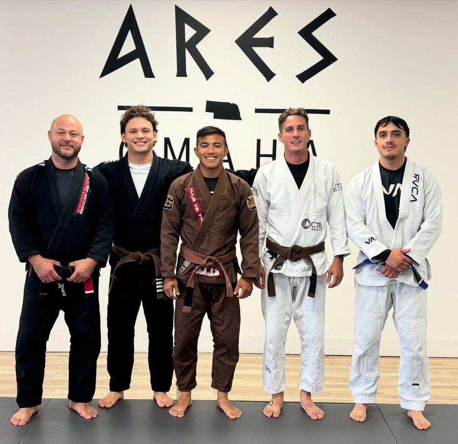 The Ares BJJ Omaha coaching staff in front of the Ares Omaha wall