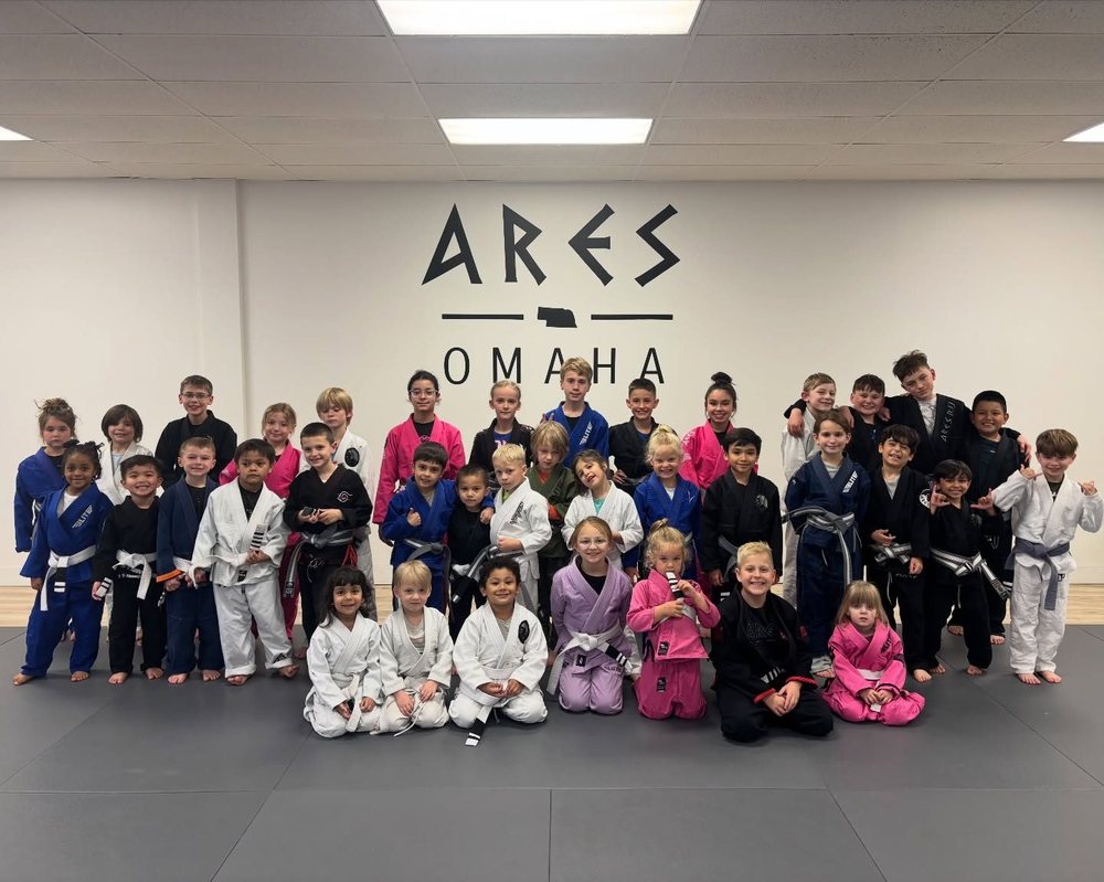 Ares BJJ Omaha kids program group photo in front of the Ares Omaha wall