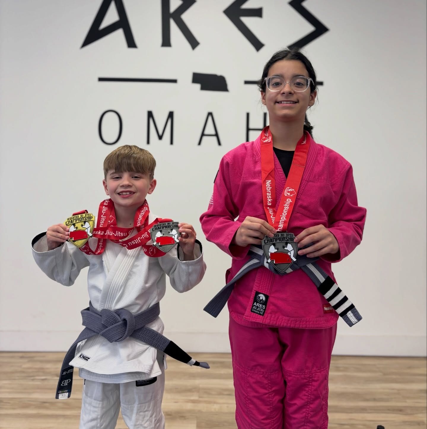 Two young Ares BJJ Omaha students holding Nebraska Jiu-Jitsu championship medals