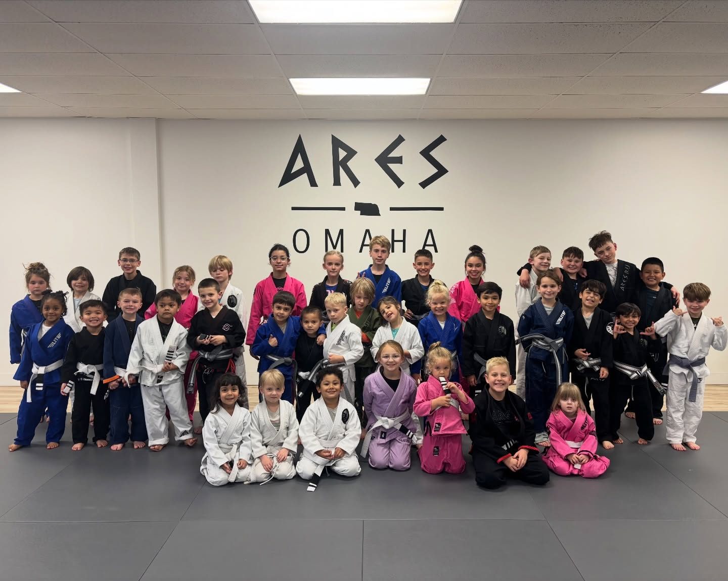 Ares BJJ Omaha kids program group photo in front of the Ares Omaha wall
